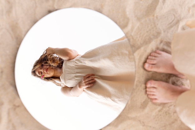Бесплатное фото Портрет молодой женщины, уверенно позирующей на открытом воздухе с круглым зеркалом