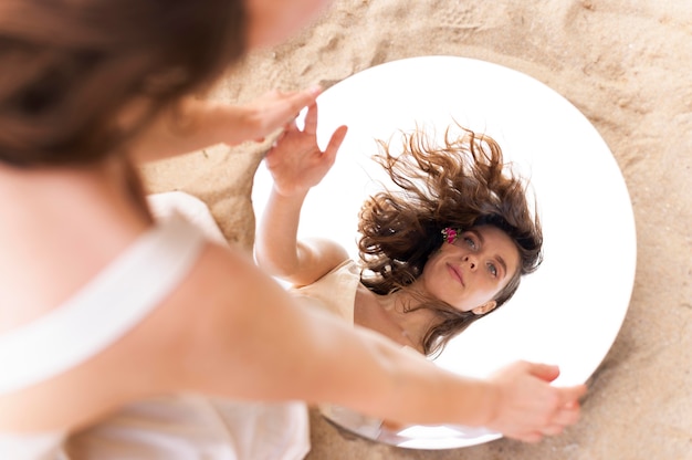 Портрет молодой женщины, уверенно позирующей на открытом воздухе с круглым зеркалом
