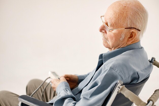 白い背景で隔離の車椅子の老人の肖像画