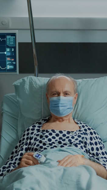 Портрет старого пациента с маской для лица, сидящего в больничной палате