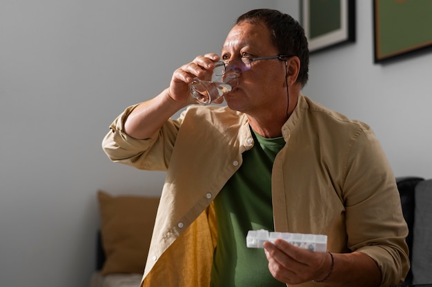 家で薬を飲む年配の男性のポートレート