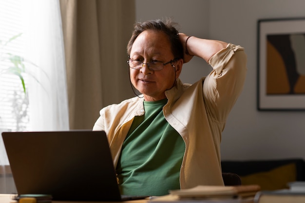 Free photo portrait of older man using laptop at home