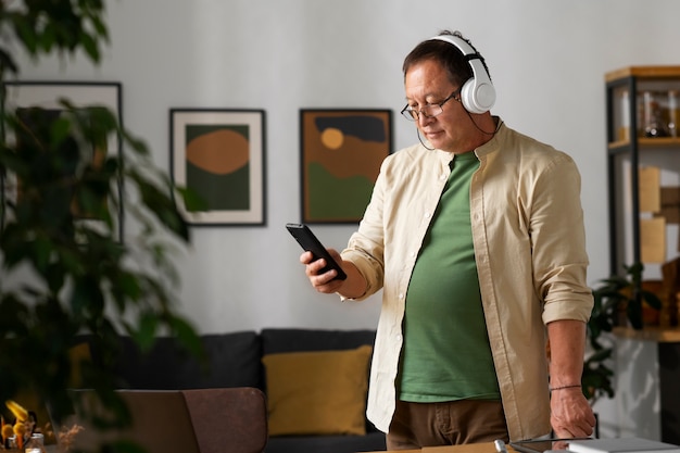 Free photo portrait of older man using smartphone at home