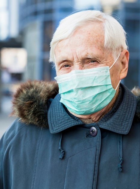 Free photo portrait of older woman in the city wearing medical mask