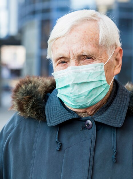 Portrait of older woman in the city wearing medical mask