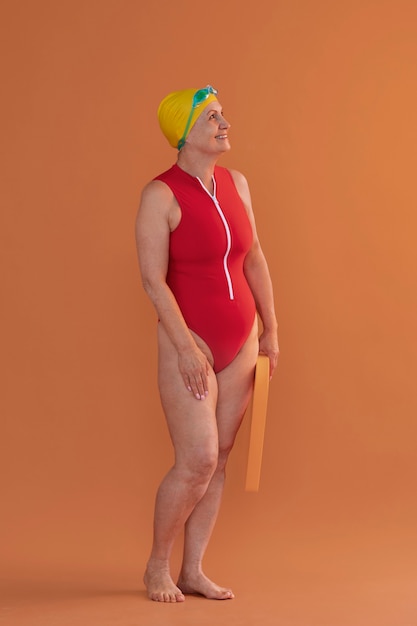 Free photo portrait of older woman in swimsuit and board