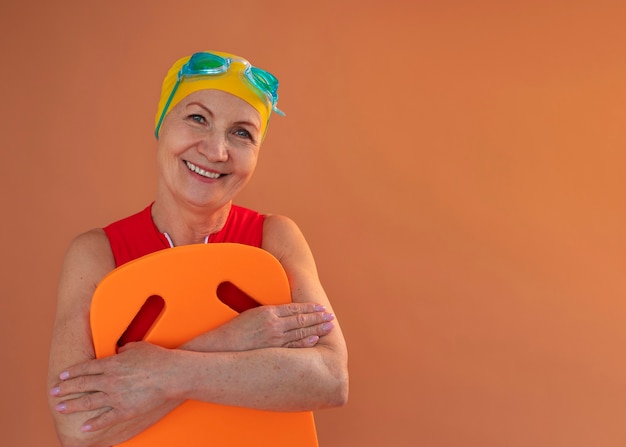 Free photo portrait of older woman in swimsuit and board