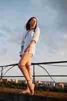 Free photo portrait of an outstanding woman in white male shirt posing on top of the building with charming scenery on the background