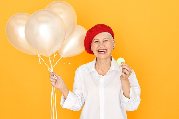 portrait of overjoyed ecstatic middle aged European woman wearing white blouse and red beret laughing