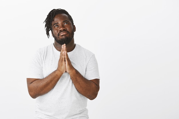 Free photo portrait of peaceful guy with braids posing against the white wall