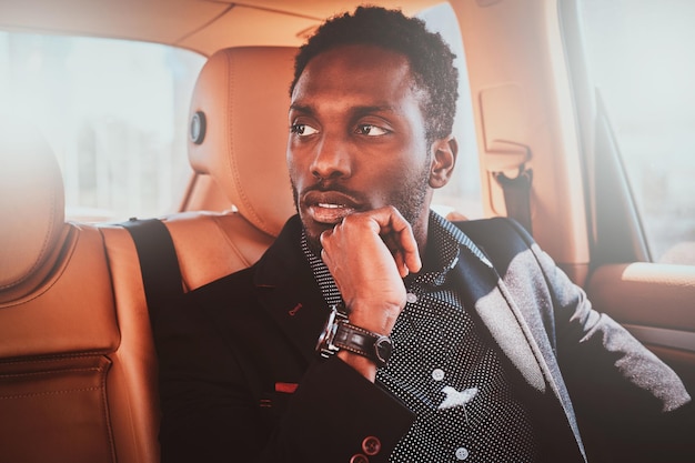 Free photo portrait of pensive elegant afro etnicity businessman in the car as a passenger.