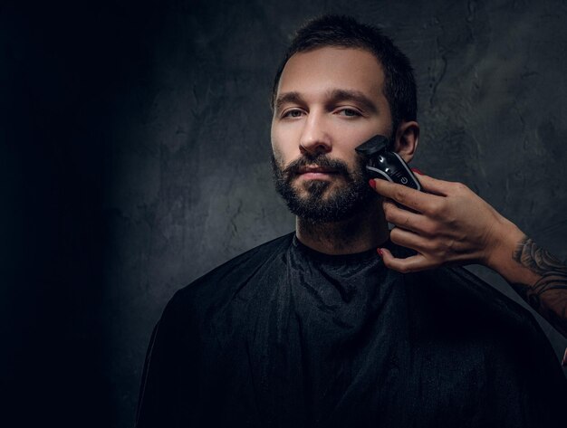 Portrait of pensive man with receive moustache and beard trimming procedure at barbershop.