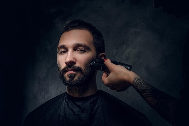 理髪店で口ひげとあごひげのトリミング手順を受け取る物思いにふける男の肖像画。