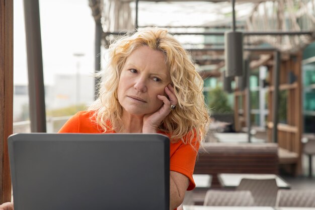 Portrait of pensive mature woman working at laptop in cafe