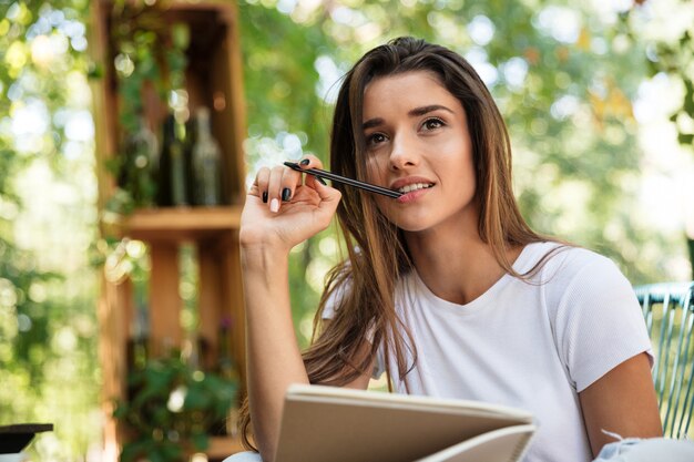 Portrait of a pensive pretty woman holding textbook