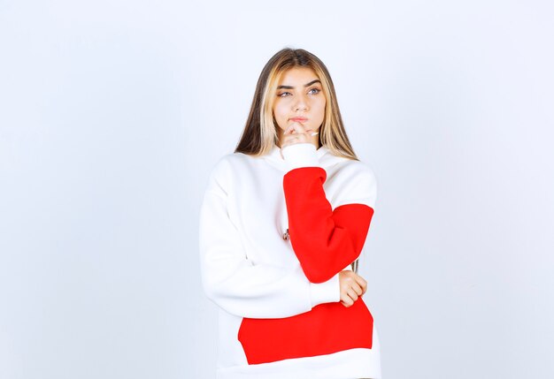 Portrait of a pensive woman in warm hoodie standing and thinking 