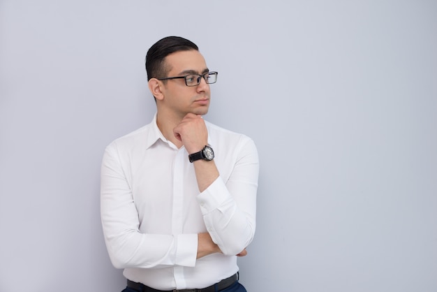 Portrait of pensive young executive standing with hand on chin