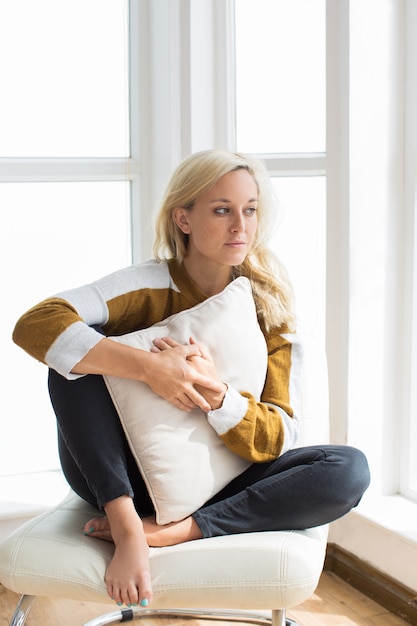 Portrait of pensive young woman sitting at home