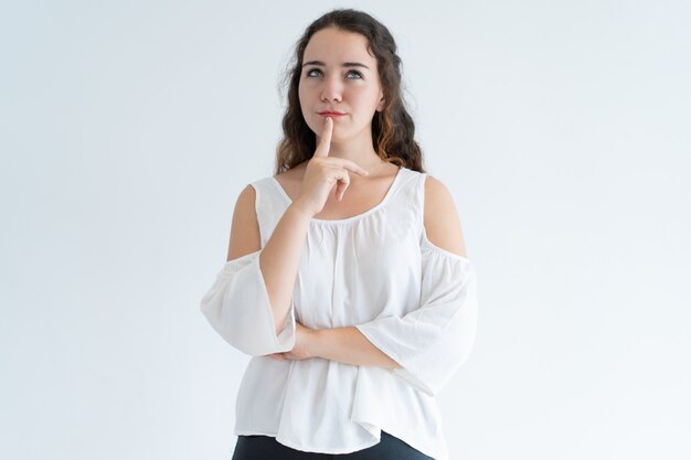 Portrait of pensive young woman standing with hand on chin