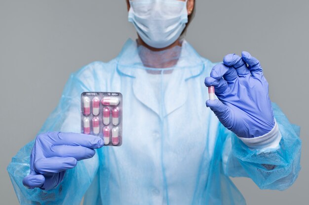 Portrait of person wearing medical gown and holding pills