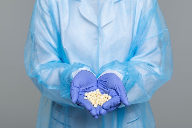 Portrait of person wearing medical gown and holding pills