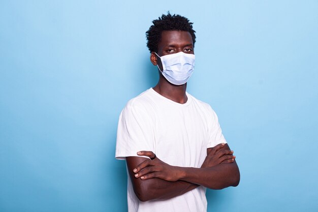 Portrait of person with face mask standing with arms crossed