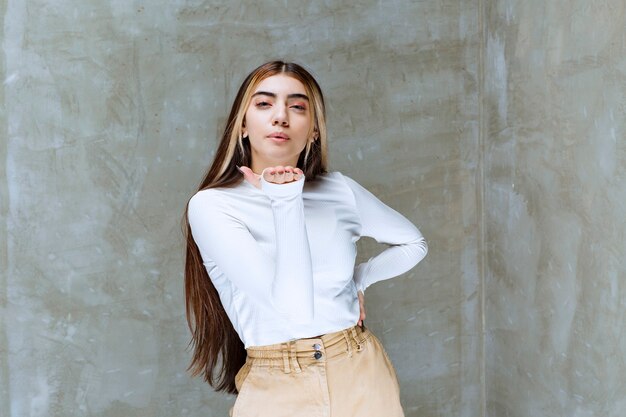 Portrait photo of a beautiful girl model standing and blowing an air kiss 