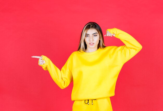 Portrait photo of a beautiful girl model standing and pointing aside 