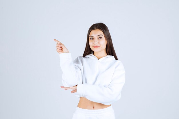 Portrait photo of a cute young girl model standing and pointing away.