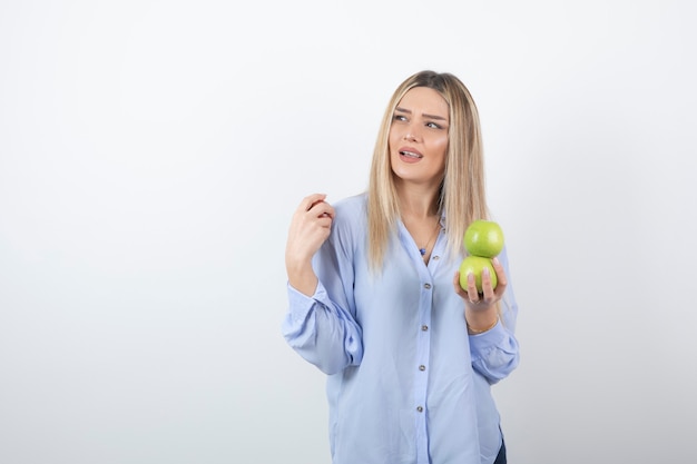 Portrait photo of a pretty attractive woman model standing and holding fresh apples .
