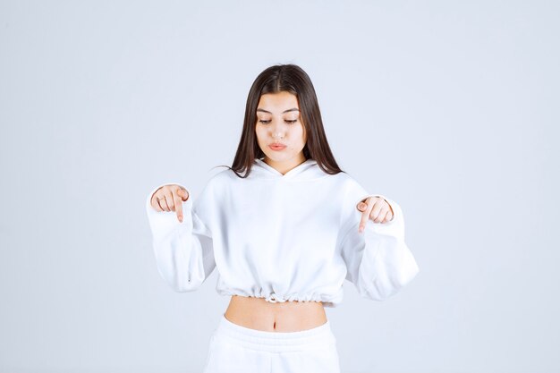 Portrait photo of a young girl model pointing down.