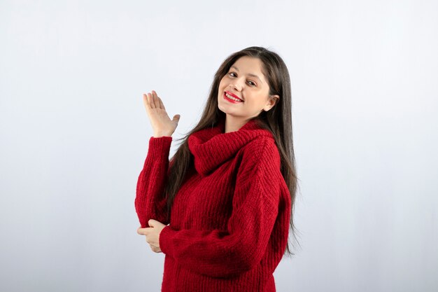 Portrait photo of a young woman model in red warm sweater standing and posing