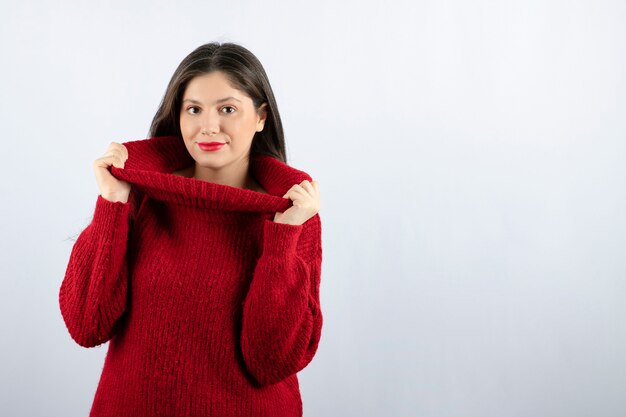 Portrait photo of a young woman model in red warm sweater standing and posing