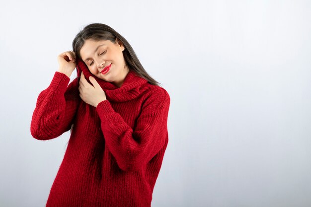 Portrait photo of a young woman model in red warm sweater standing and posing