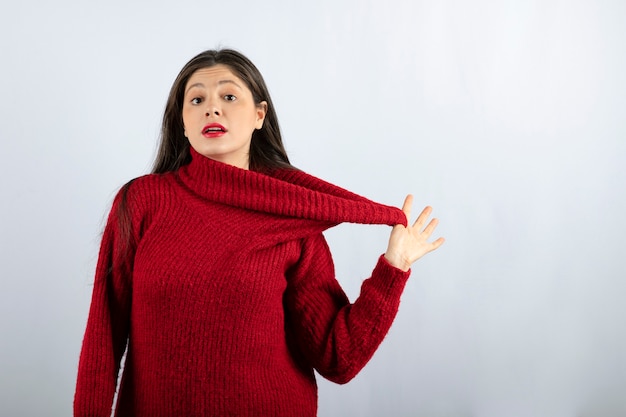 Портретное фото молодой женщины модели в красном теплом свитере стоя и позирует