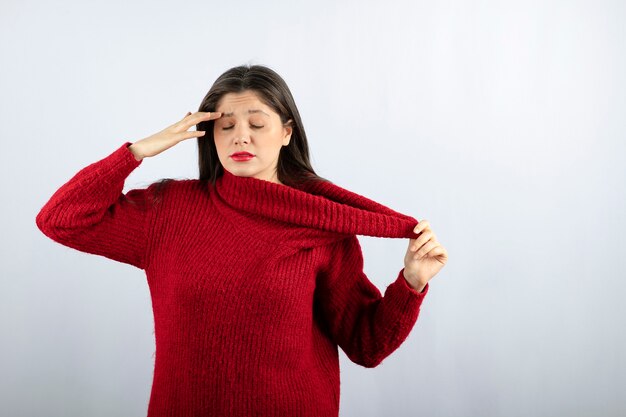 Portrait photo of a young woman model in red warm sweater standing and posing