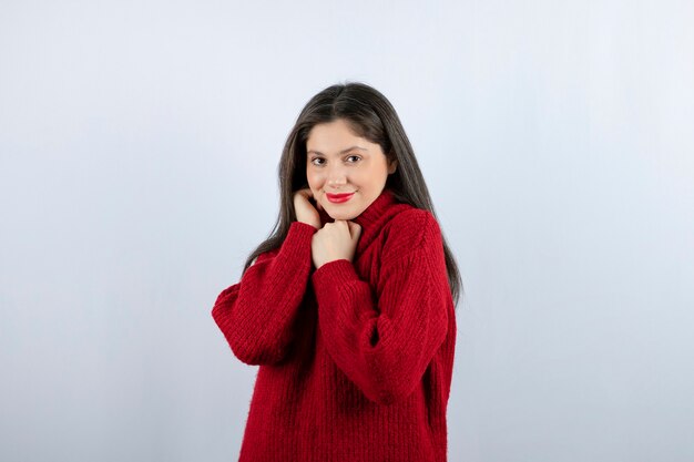 Portrait photo of a young woman model in red warm sweater standing and posing