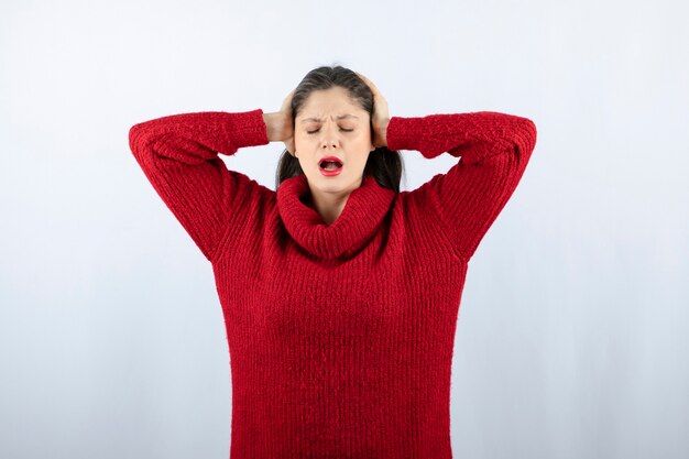 Portrait photo of a young woman model in red warm sweater standing and posing