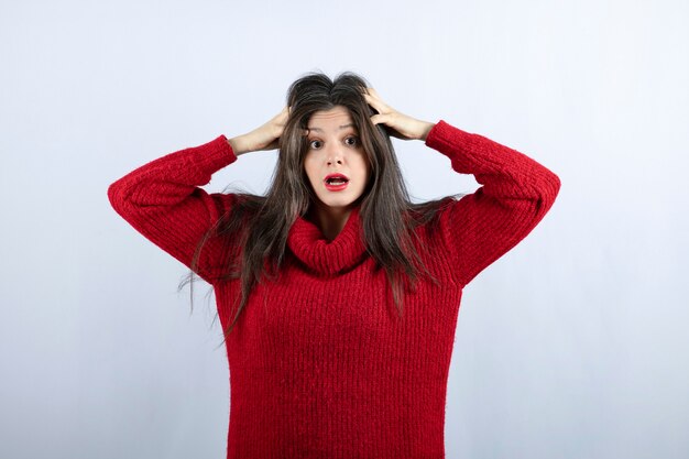 Portrait photo of a young woman model in red warm sweater standing and posing