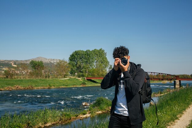 Portrait of photographer taking picture near river