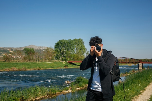 Портрет фотографа фотографируя около реки