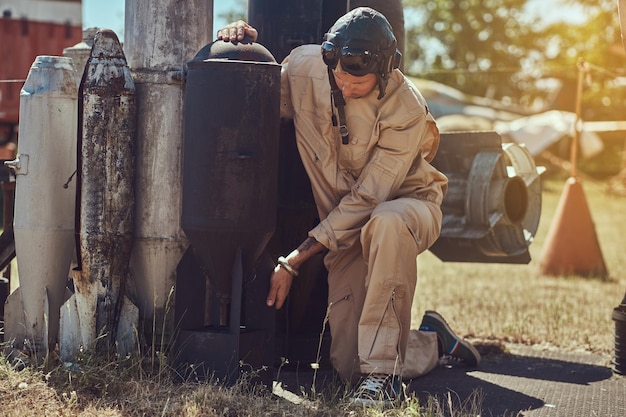 Free photo portrait of a pilot in uniform and flying helmet near to combat bombs for a bomber aircraft in an open-air museum.