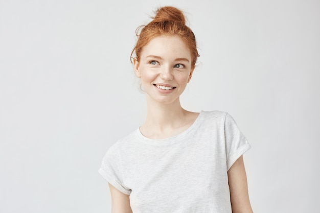 Portrait of playful beautiful ginger woman with freckles smiling.