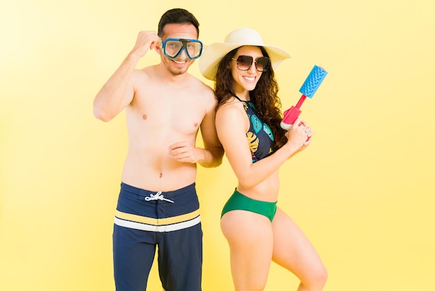 Portrait of a playful couple with snorkel googles and a water gun ready to have a great time at the beach and by the pool during their summer vacations