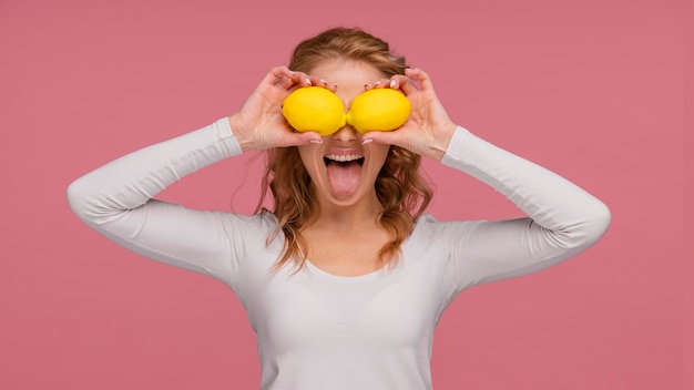 Portrait playful woman holding lemons and  laughs