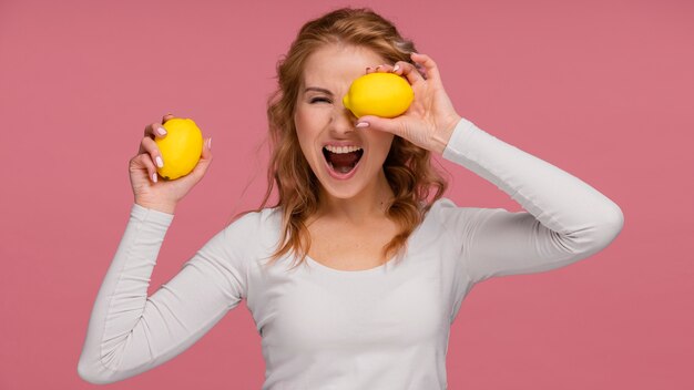 Portrait playful woman holding lemons and  laughs