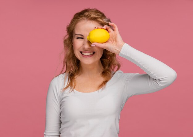 Portrait playful woman holding lemons and  laughs