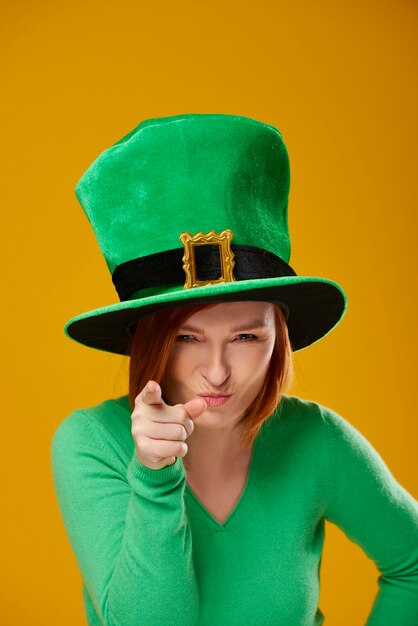 Portrait of playful woman with leprechaun's hat pointing at camera