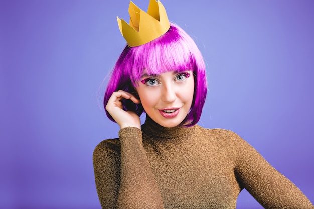 Portrait playful young woman with cut purple hair, gold crown, luxury dress having fun. Great celebration, carnival, princess style, birthday, excited, positive emotions.