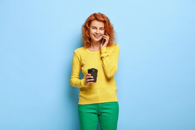 見栄えの良いセクシーな女性の肖像画は、コーヒーを飲み、スマートフォンを介して呼び出します